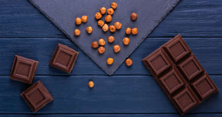 Broken chocolate bar slice with hazelnut on blue backgroundの写真素材
