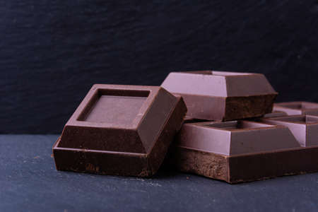 Broken chocolate bar slice on grey background