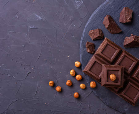 Broken chocolate bar slice with hazelnut on grey backgroundの写真素材