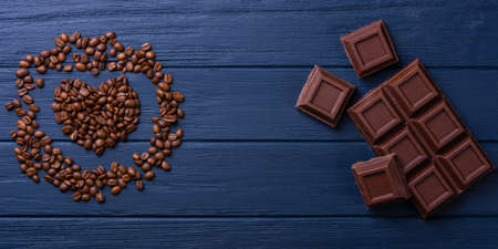 Broken chocolate bar slice with coffee seeds on blue backgroundの写真素材