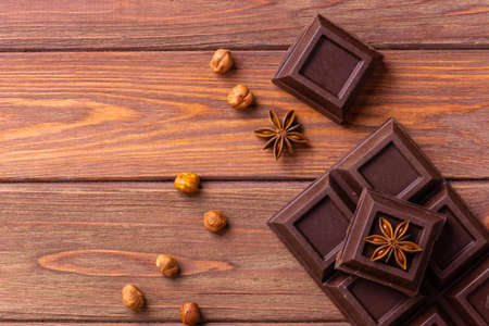 Broken chocolate bar slice with hazelnut on wooden background