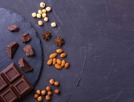 Broken chocolate bar slice with almond and hazelnut on grey backgroundの写真素材
