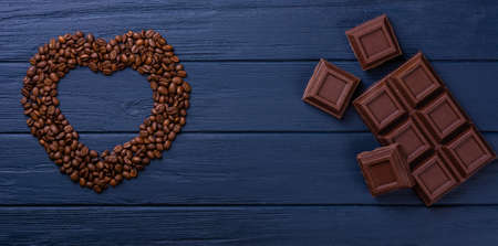 Broken chocolate bar slice with coffee seeds on blue backgroundの写真素材