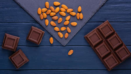 Broken chocolate bar slice with almond on blue backgroundの写真素材