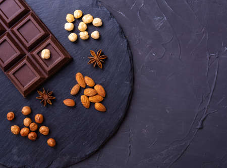 Broken chocolate bar slice with almond and hazelnut on grey backgroundの写真素材