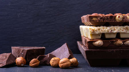 Broken chocolate bar slice with hazelnut on grey background