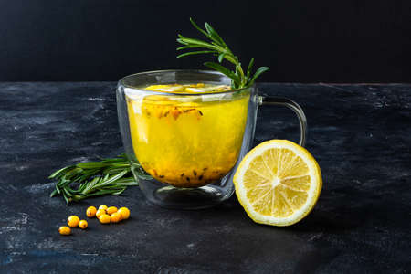 Transparent glass cup with bright yellow tea on dark backgroundの写真素材