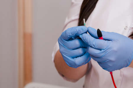 A handsome cosmetologist with long dark hair is performing an electrolysis procedure. In the...