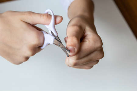 Child cuts his fingernails with scissors on a white background. Close-up.の写真素材