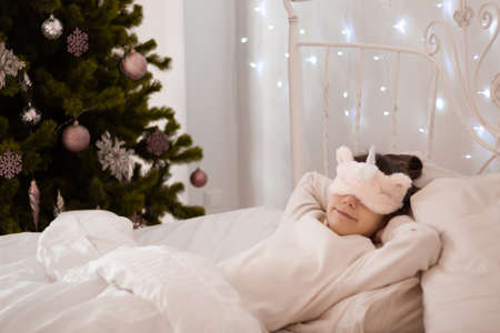 A funny dark-haired girl wakes up in the morning in bed. Place for an inscription.