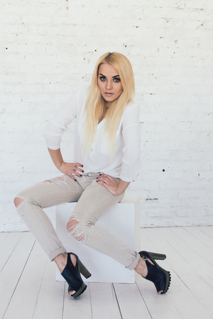 Young sexy blond woman in white shirt and jeans and black shoesの写真素材