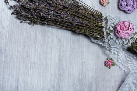 Dried lavender bunches on light wooden table, pink and violet roses on white wooden background. Overhead view, top viewの写真素材
