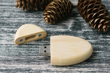 Creative wooden usb stick on dark background. Wooden USB flash drive with fir cone on white and...