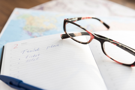Open daily, pen and a glasses on the desktop with maps. Travel concept