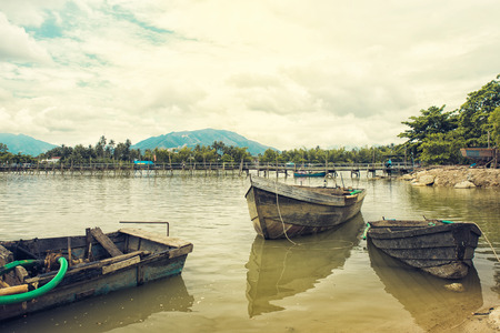Fishing wooden boat on a river. Boat on a river in Vietnam. Old bridge on background. toned photoの写真素材