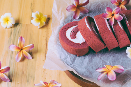 Roll Red velvet cupcakes without cream. Cakes on baking parchment. Rustic wooden background with plumeria flowersの写真素材