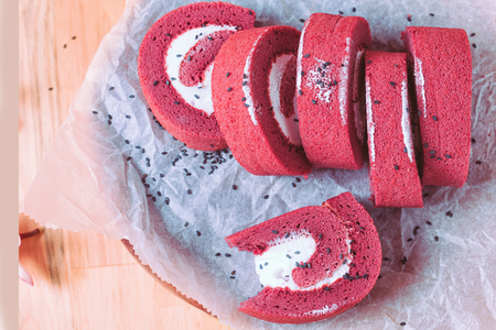 Roll Red velvet cupcakes without cream. Cakes on baking parchment. Rustic wooden background with plumeria flowersの写真素材