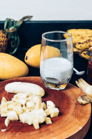 Glass of chia seeds pudding with mango. Basil seeds in coconut milk. A banch of bananas and a sliced ??banana on a tableの写真素材