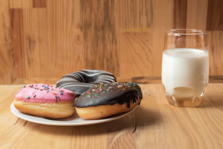 Doughnuts with chocolate and pink frostin on wooden table. Baked unhealthy Sweet food.の写真素材