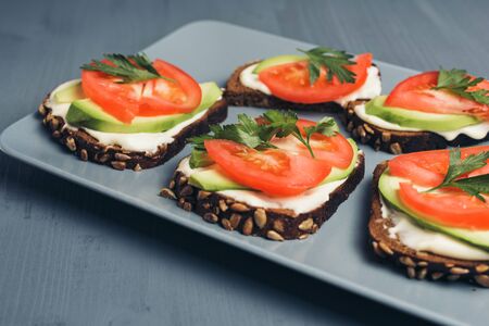 Healthy green veggie food concept. Yammy toast with cream cheese, avocado and juicy red tomato on a...