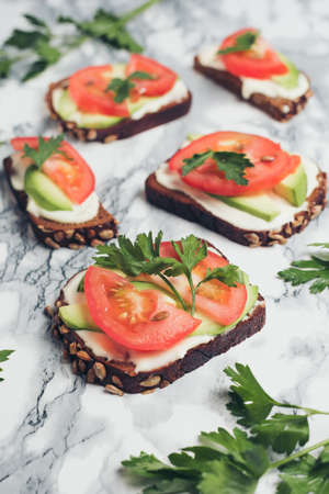 Healthy green veggie food concept. Yammy toast with cream cheese, avocado and juicy red tomato on...