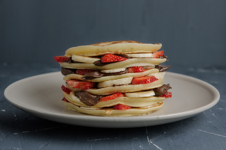 Plate full of pancakes with strawberries, bananas and chocolate creamの写真素材