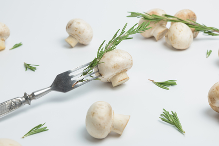 Common mushroom on a vintage fork. Sliced ??champignon and rosemary on the stainless steel fork isolated on a white backgroundの写真素材