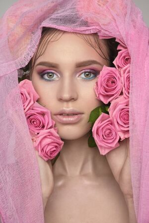 Studio portrait of a beautiful young woman. Fashionable brunette model with nude pink lips and perfect colorfull makeup in scarf on headの写真素材