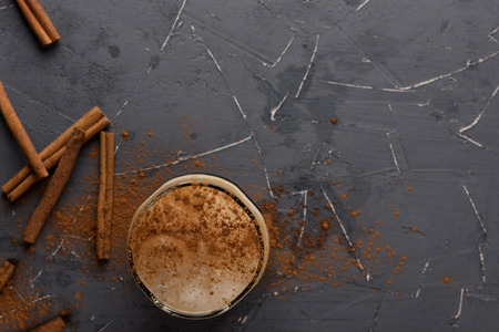 Iced espresso with cream in a glass with cinnamon sticks on grey stone table. Copy spaceの写真素材
