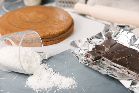 Dark chocolate and biscuit cake layer. Chocolate bar in foil on gray background. Copy spaceの写真素材