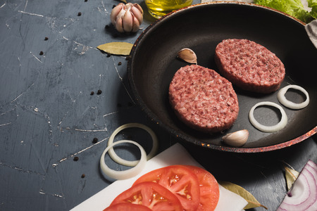 Organic fresh minced meat cutlets. Raw Ground beef meat Burger steak with ingredients in a frying...