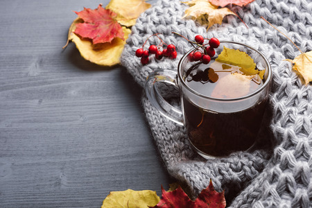 Cup of tea and gray plaid. Hot coffee and autumn leaves on wood background. Fall concept