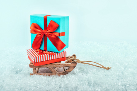 Sledge on snow with presents. Red, blue and yellow Christmas gift boxes in a sleighの写真素材