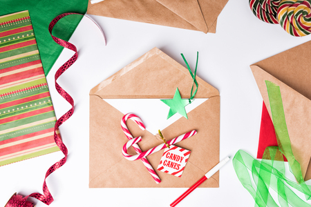 Workspace with brown craft envelope. Flat Lay Christmas or Party Background with ribbons, candy canes, decorations and wrapping paper.の写真素材
