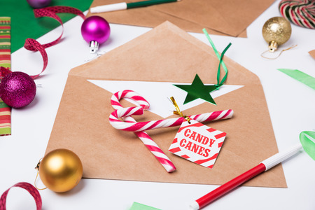 Workspace with brown craft envelope. Flat Lay Christmas or Party Background with ribbons, candy canes, baubles, Star tag, decorations and wrapping paper.の写真素材