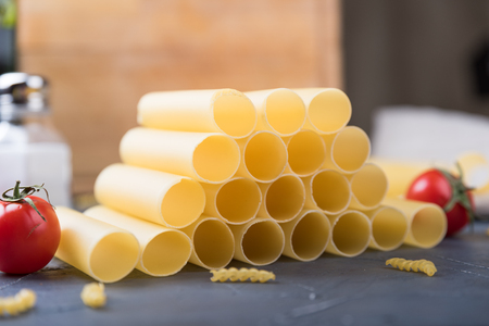 Raw cannelloni on a gray table. Traditional italian food ingredients. Tomatos, pasta, sauceの写真素材