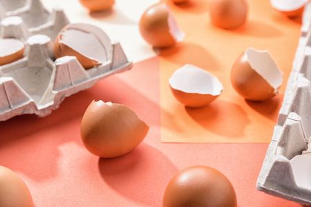 Eggs on geometric orange background. Broken egg shell on a pink paper. Pattern, easter concept....