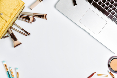 Workspace with laptop, paper clips, bookmarks, make-up brushes, powder. Top view with copy spaceの写真素材