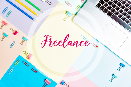 Colorful office desk table, flat lay. Workspace with laptop, paper clips, pens, bookmarks, green plant. Top view with copy space, letteringの写真素材