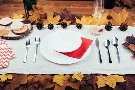 Top view of beautiful autumn decor and cutlery on wood table served for thanksgiving dinner. Fall...