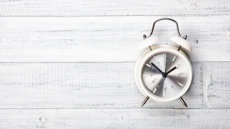 The vintage alarm clock on the white wooden table background, flat Lay, top view. Copy space for your textの写真素材