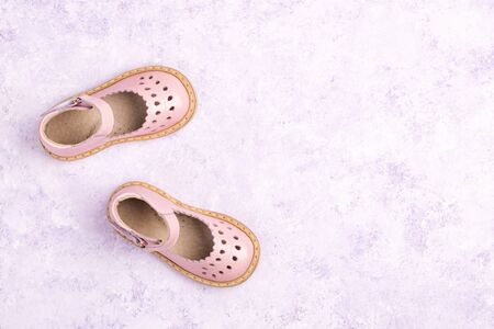 Summer Pink Baby girl shoes on violet marble background. Top view trendy leather sandal, flat lay....