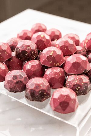 Exclusive handcrafted chocolate candy. Luxury handmade bonbon decorated with red paint on white...