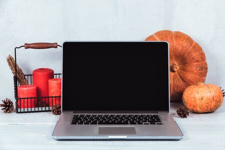 Orange pumpkins and red candles near a laptop computer on a table. Autumn season timeの写真素材