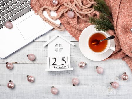 Workspace with pink Christmas tree ornaments, laptop, cup of tea. Top view of cozy office wooden desk. Christmas background, flat lay.の写真素材