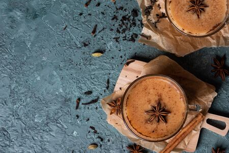 Glass cups of traditional Indian masala chai on dark green texture background. Ingredients of beverage black tea, ginger, cinnamon, cardamom, anise starsの写真素材