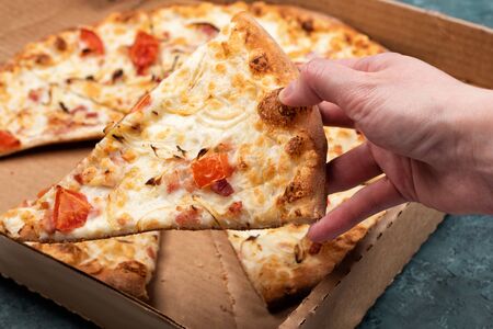 Pizza in a cardboard box on a dark green textural concrete background. Copy space for your text. Top view, flat lay. Takeaway food conceptの写真素材