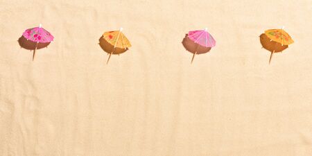 Sun cocktail umbrellas on hot sand.の写真素材