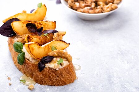 Sweet italian antipasti snacks bruschetta with cream cheese, caramelized pear, honey, basil on marble table.の写真素材