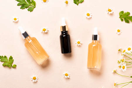 Glass bottles of essence or serum with chamomile flowers.の写真素材